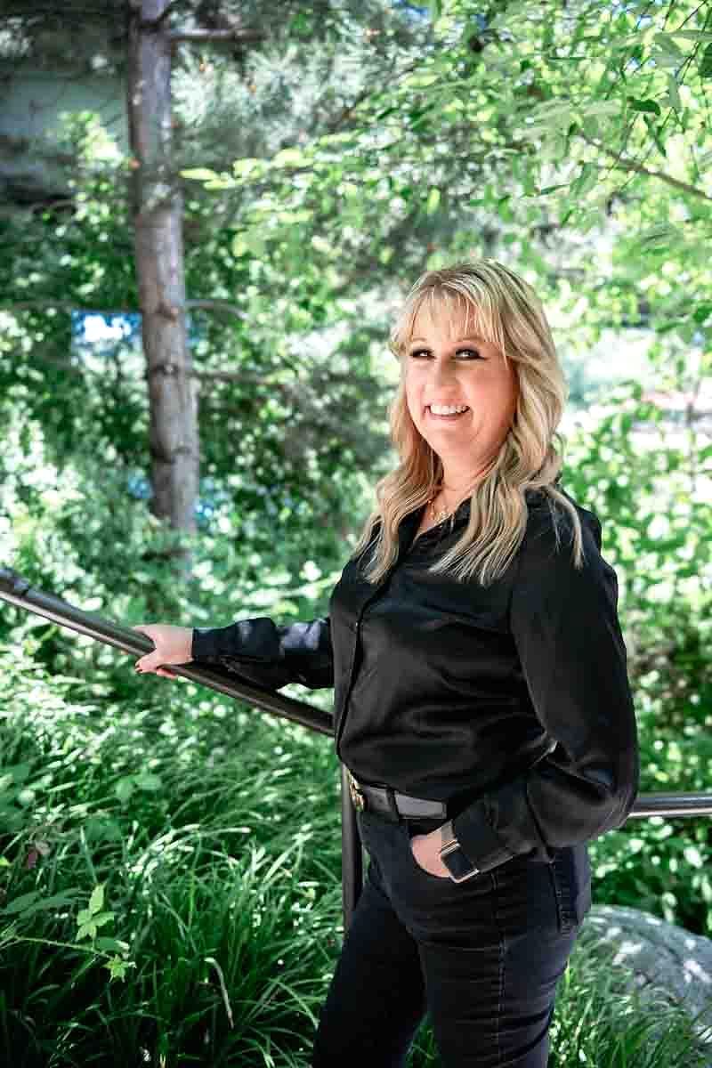 A Salon Sister in a black satin blouse by a railing