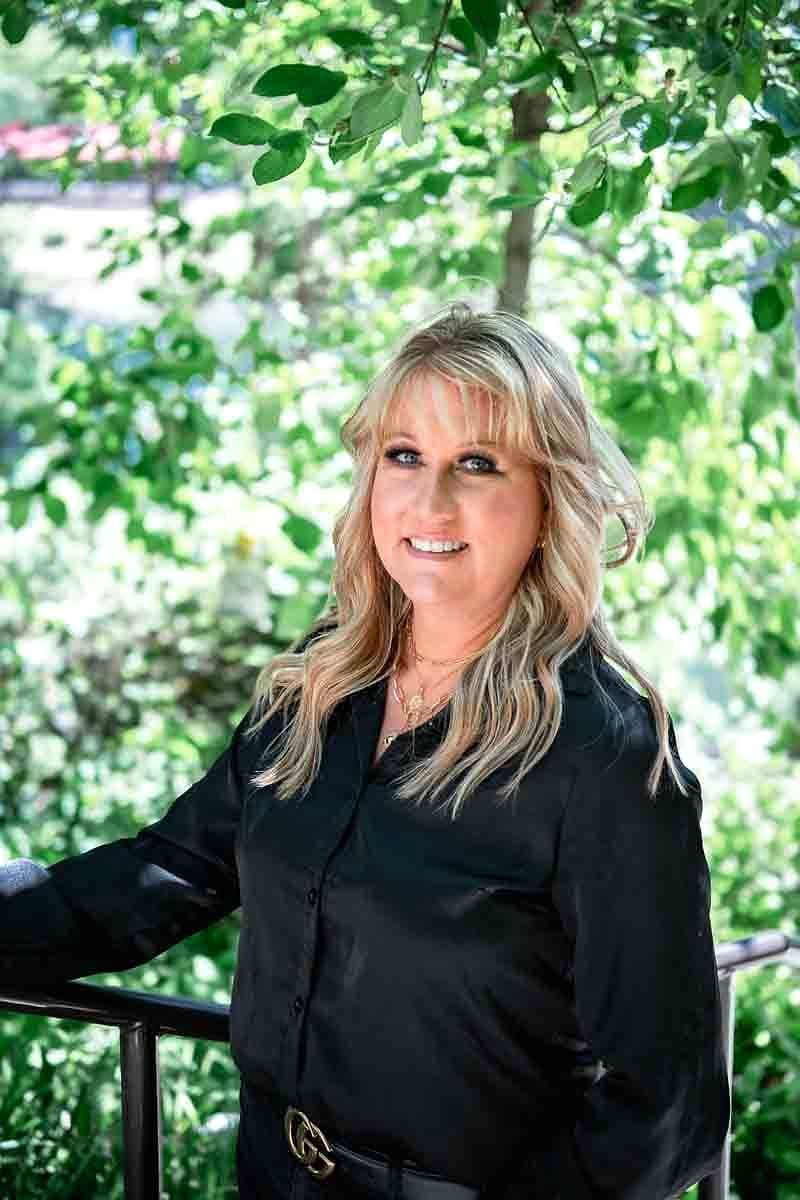 A Salon Sister in a black blouse among greenery