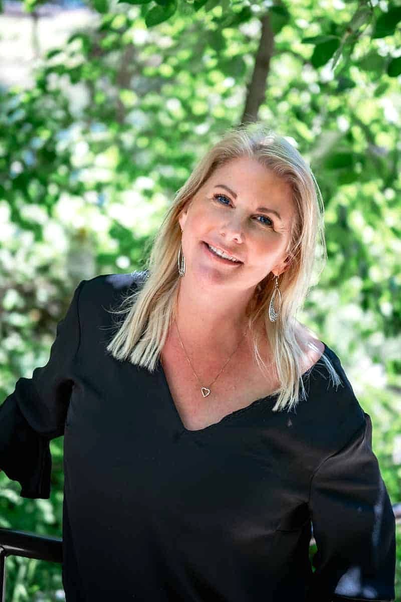 A Salon Sister smiling in front of green foliage