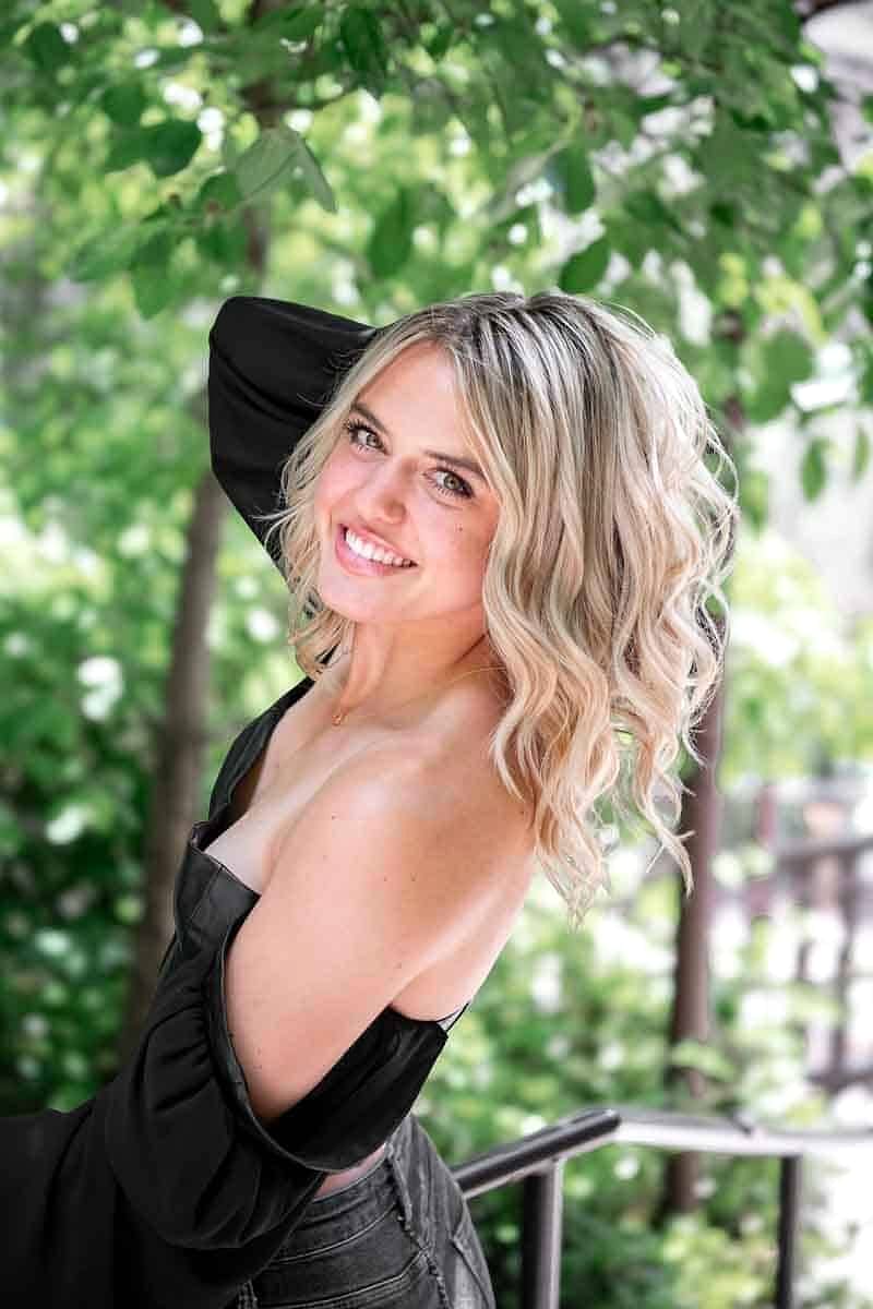 One of the Salon Sisters laughing, hand in her curled blonde hair